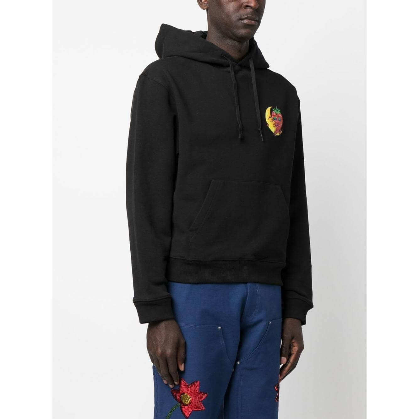 Black Sky High Farm hoodie with chest graphic and drawstring, featuring sustainable cotton, modeled on a person with blue pants.