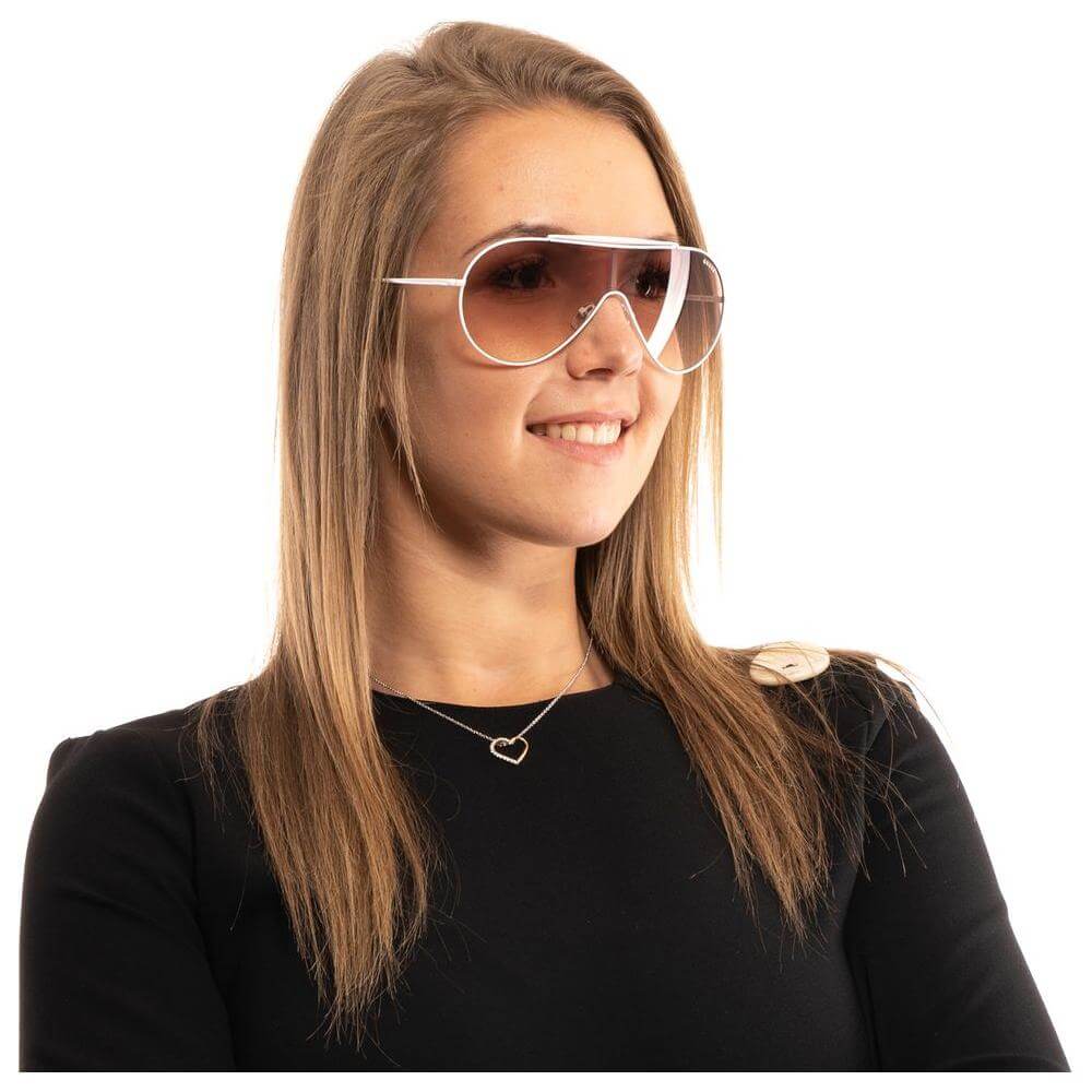 Fashionable woman wearing Guess white sunglasses with brown gradient lenses and metal frame.