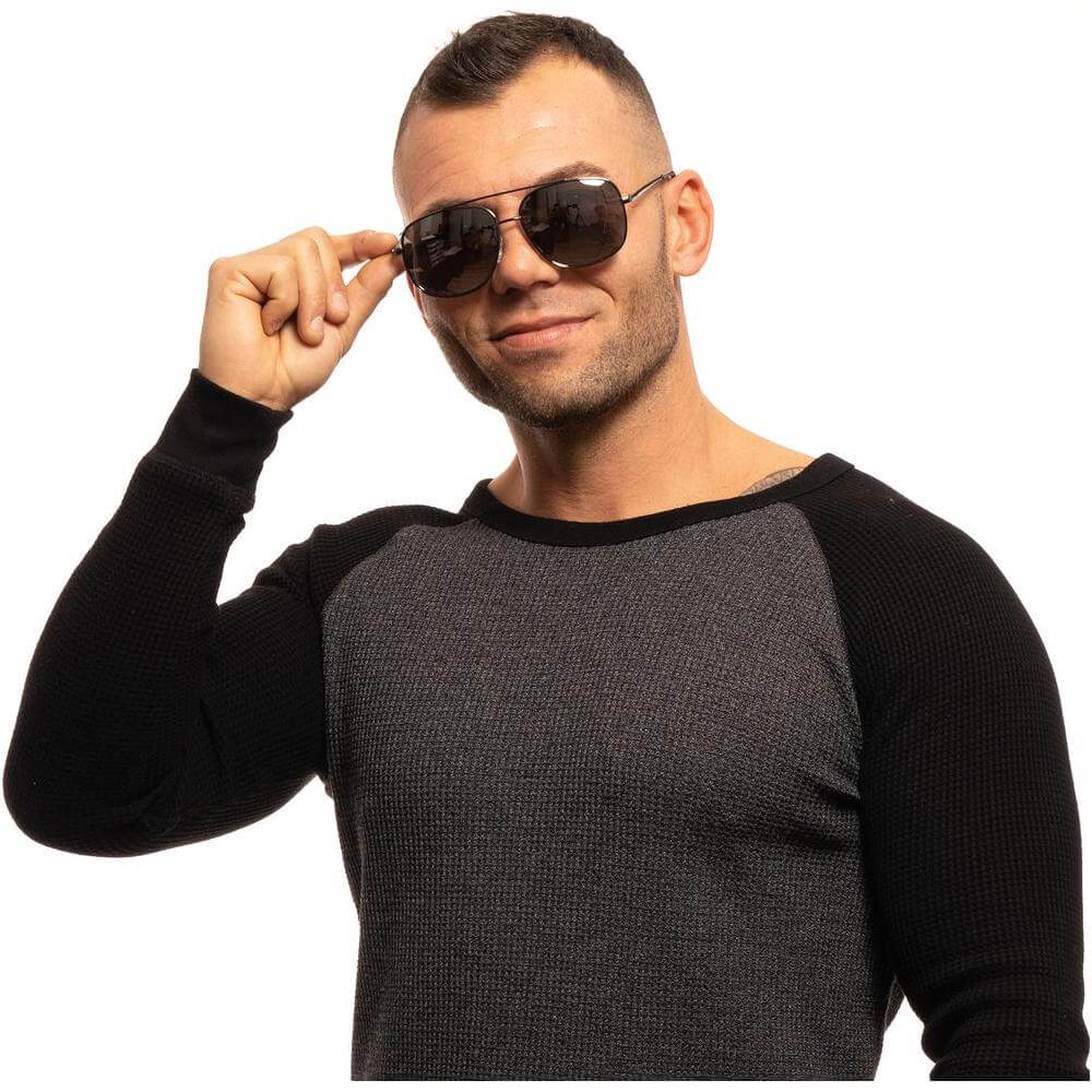 Man wearing Guess gray aviator sunglasses with mirrored lenses and gunmetal metal frame, posing confidently in casual outfit.