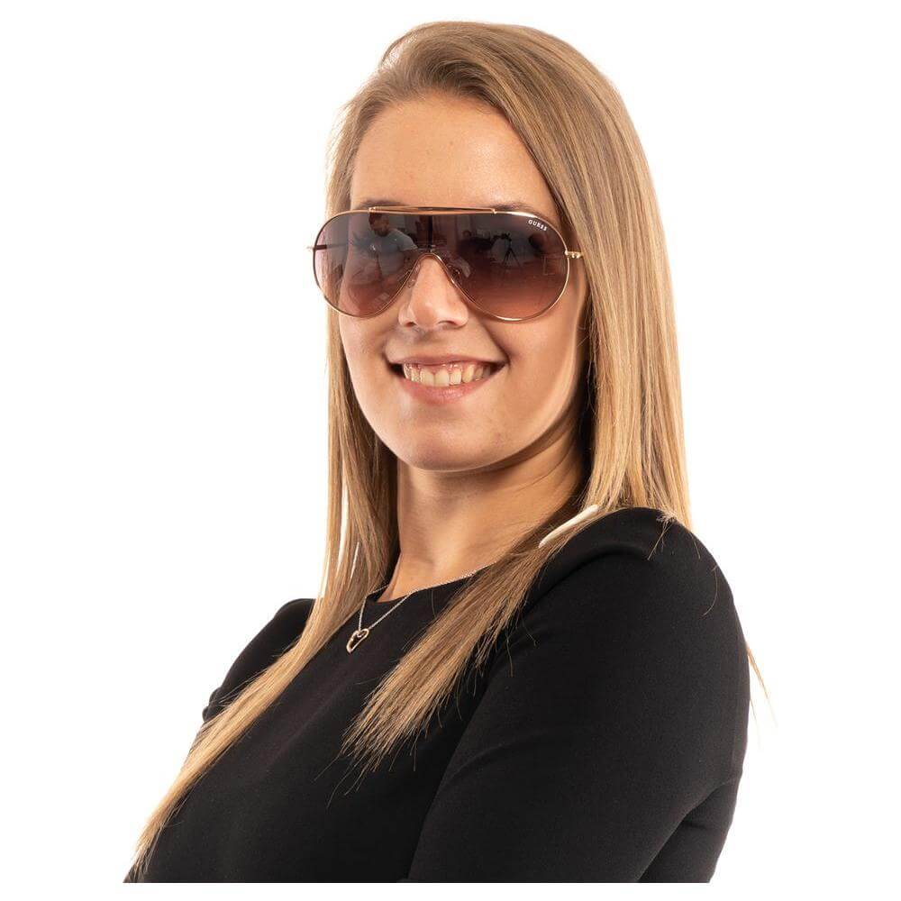 Woman wearing Guess rose gold sunglasses with purple gradient lenses and metal frame, showcasing a stylish and modern look.