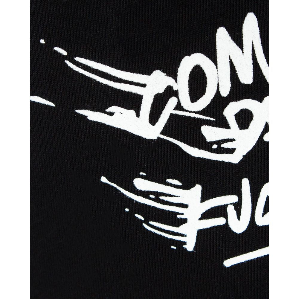 Close-up of Comme Des Fuckdown logo on black cotton fabric, featuring bold white text and graphic design on men's sweatpants.