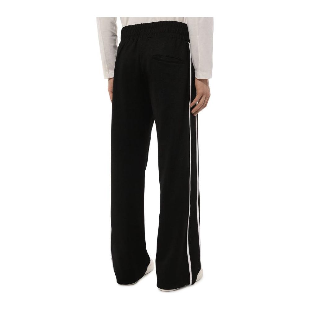 Comme Des Fuckdown black polyester tracksuit trousers with white side bands and front logo print, shown from the back view.