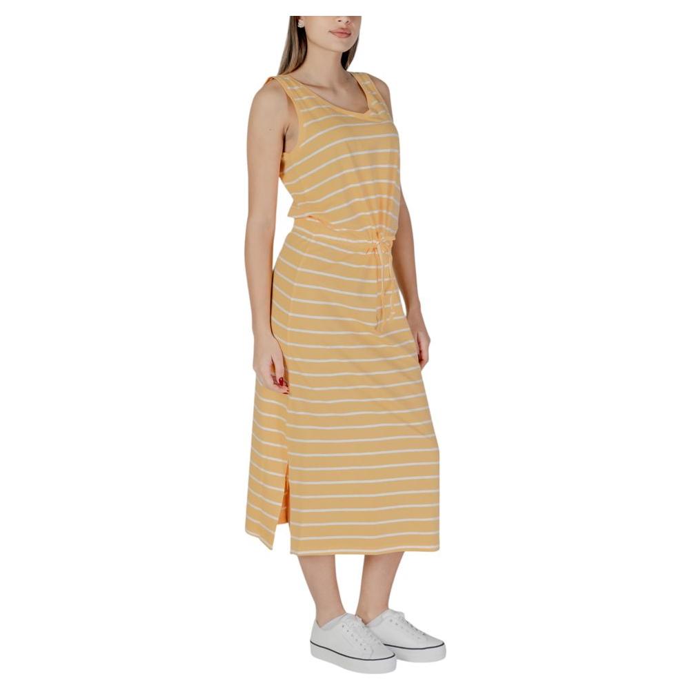 Woman wearing B.Young yellow cotton dress, sleeveless, spring/summer style, with white sneakers. Made of 95% cotton, 5% elastane.
