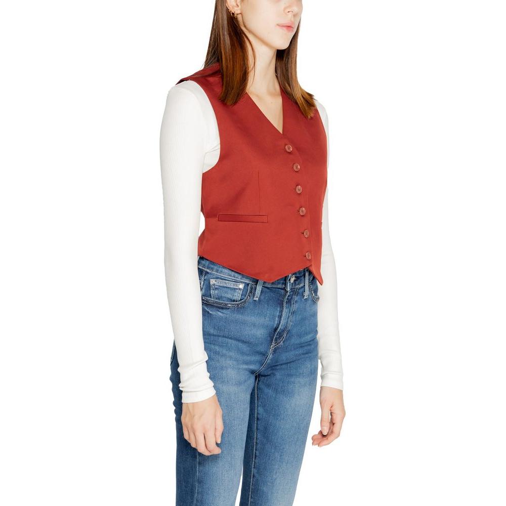 Woman wearing a Vero Moda red polyester vest, fall/winter collection, paired with a white long-sleeve top and blue jeans.