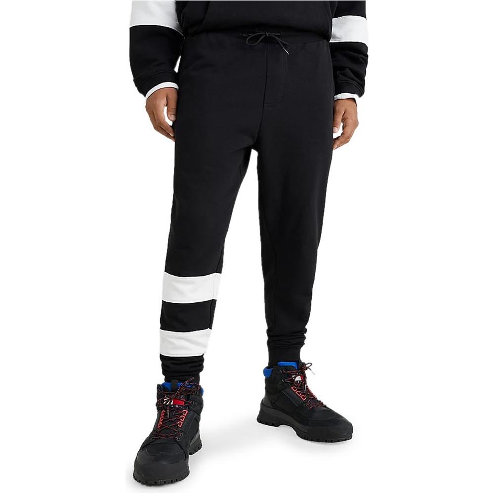 Man wearing Tommy Hilfiger black cotton men's sport pants from the Spring/Summer collection with white stripe detail.