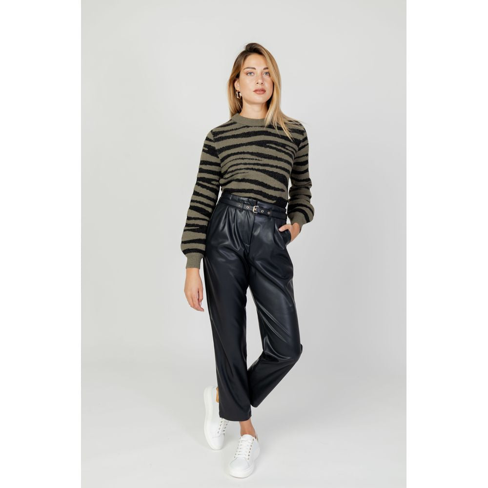Woman wearing a Jacqueline De Yong green striped sweater and black leather pants standing against a plain background