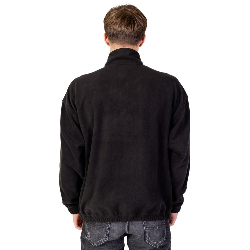 Back view of a man wearing a Tommy Hilfiger black recycled polyester sweater, part of the fall/winter collection, hoodless design.