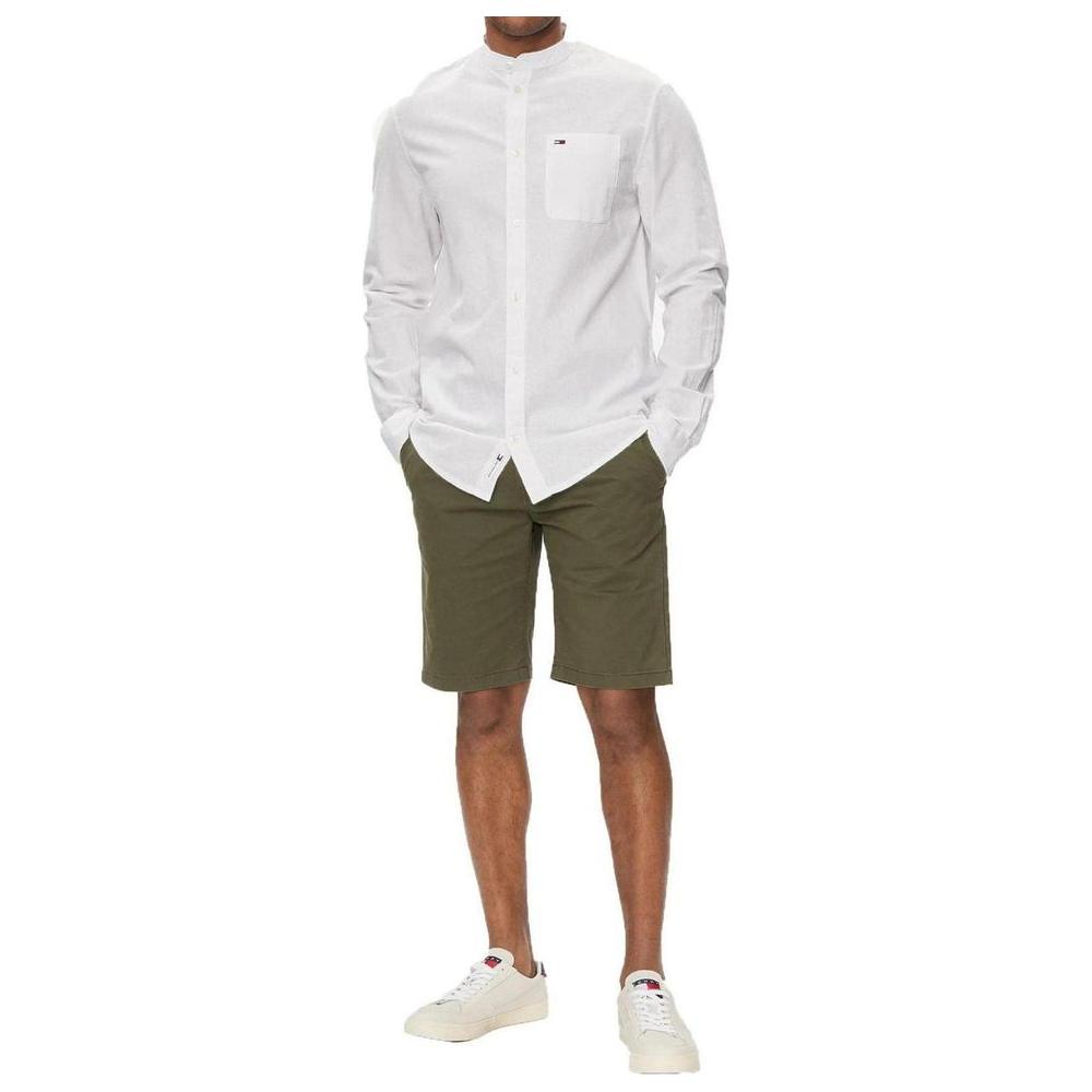 Model wearing Tommy Hilfiger green organic cotton Bermuda shorts with white shirt, perfect for spring/summer casual style.
