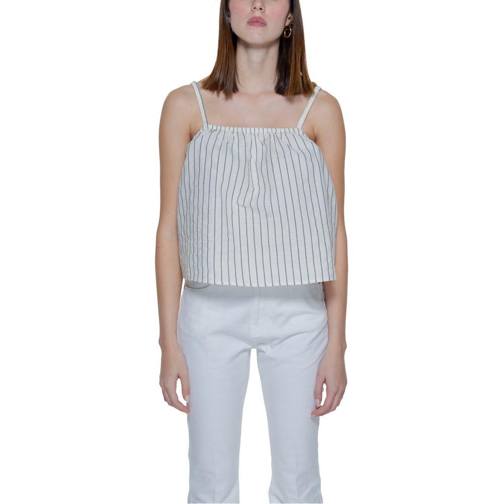 Woman wearing Vero Moda beige striped tank top made of organic cotton, part of spring/summer collection, paired with white pants.