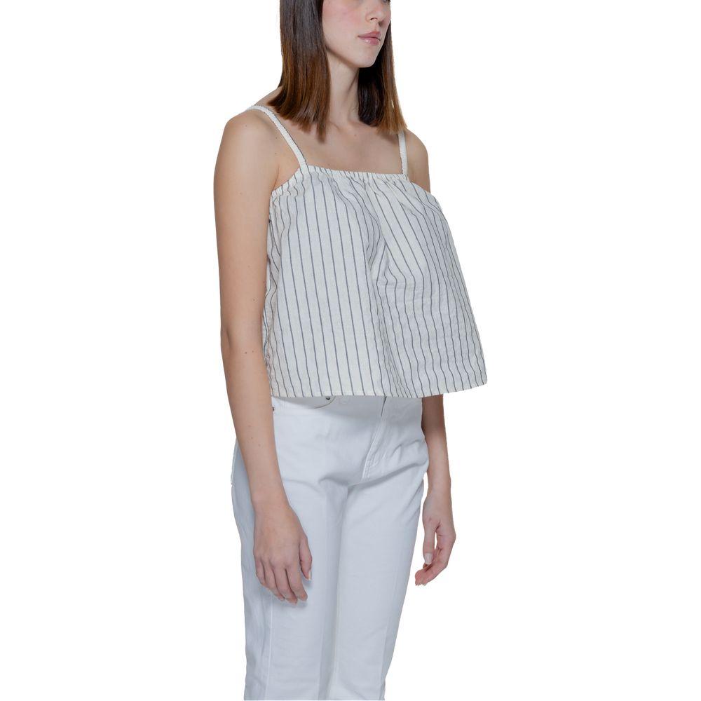 Woman wearing a striped sleeveless top with white pants, showcasing spring-summer fashion for women.