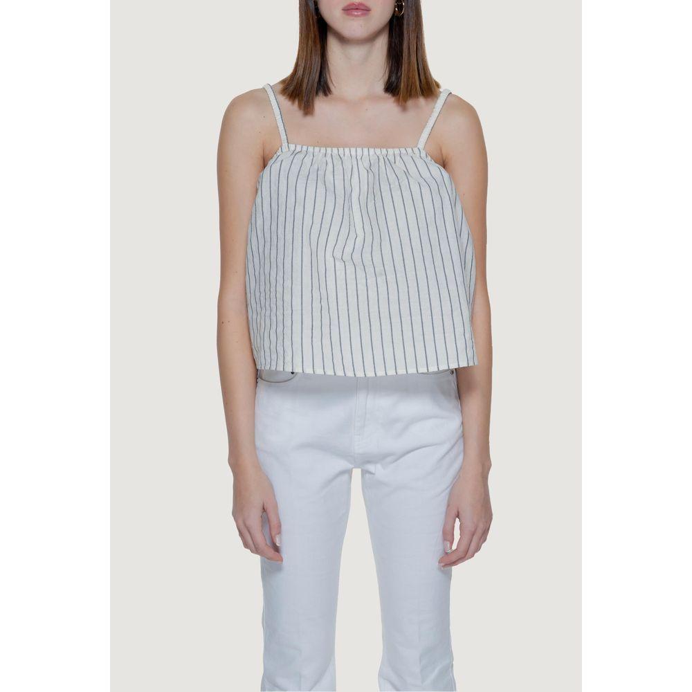 Woman wearing Vero Moda beige striped tank top, spring/summer collection, made of organic cotton blend, paired with white pants.