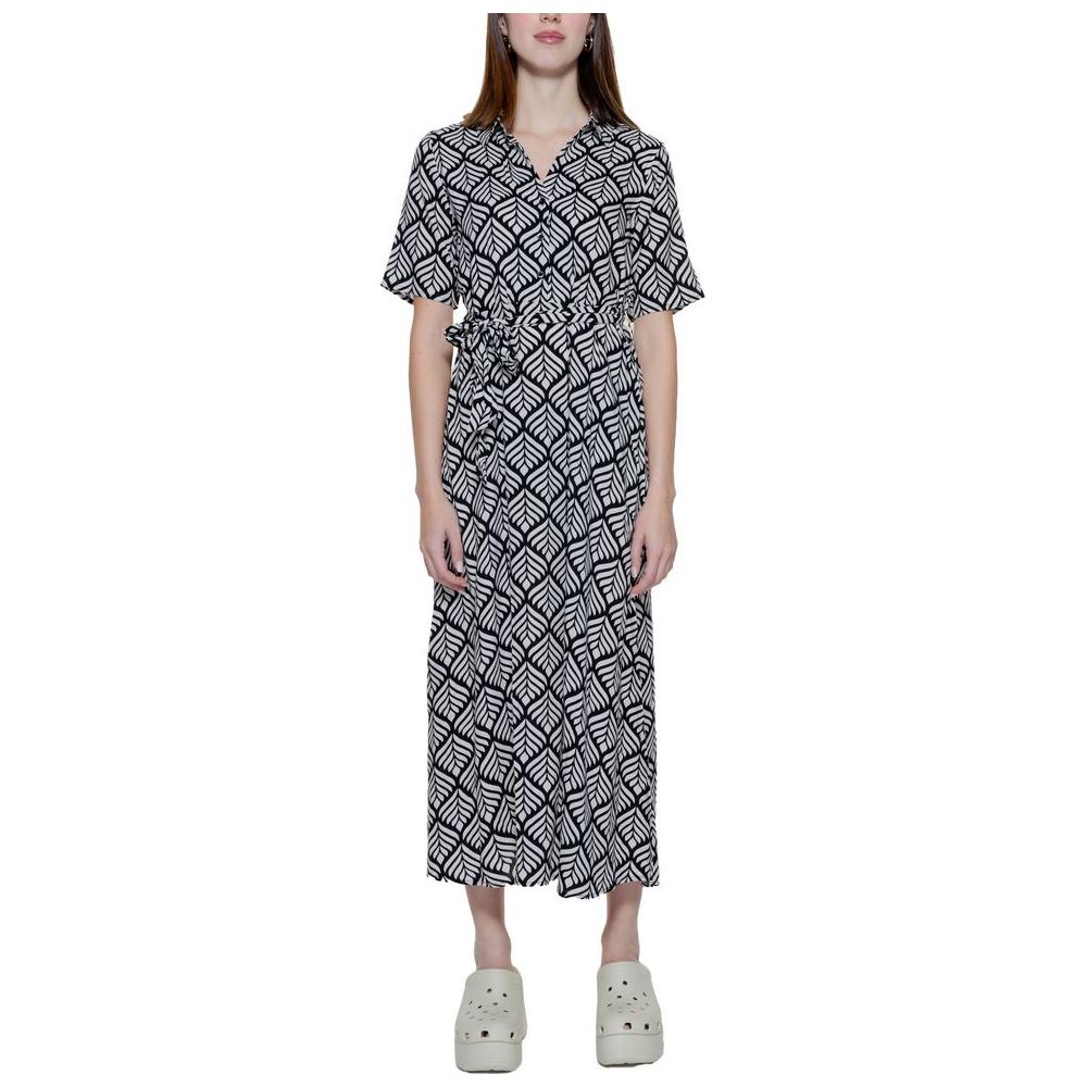 Woman wearing a black and white patterned long dress with half sleeves and a relaxed fit, paired with white clogs.