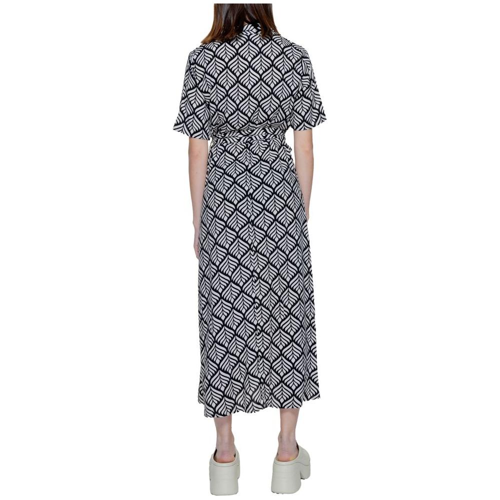 Back view of a woman wearing a long black and white patterned dress with short sleeves, paired with platform sandals.