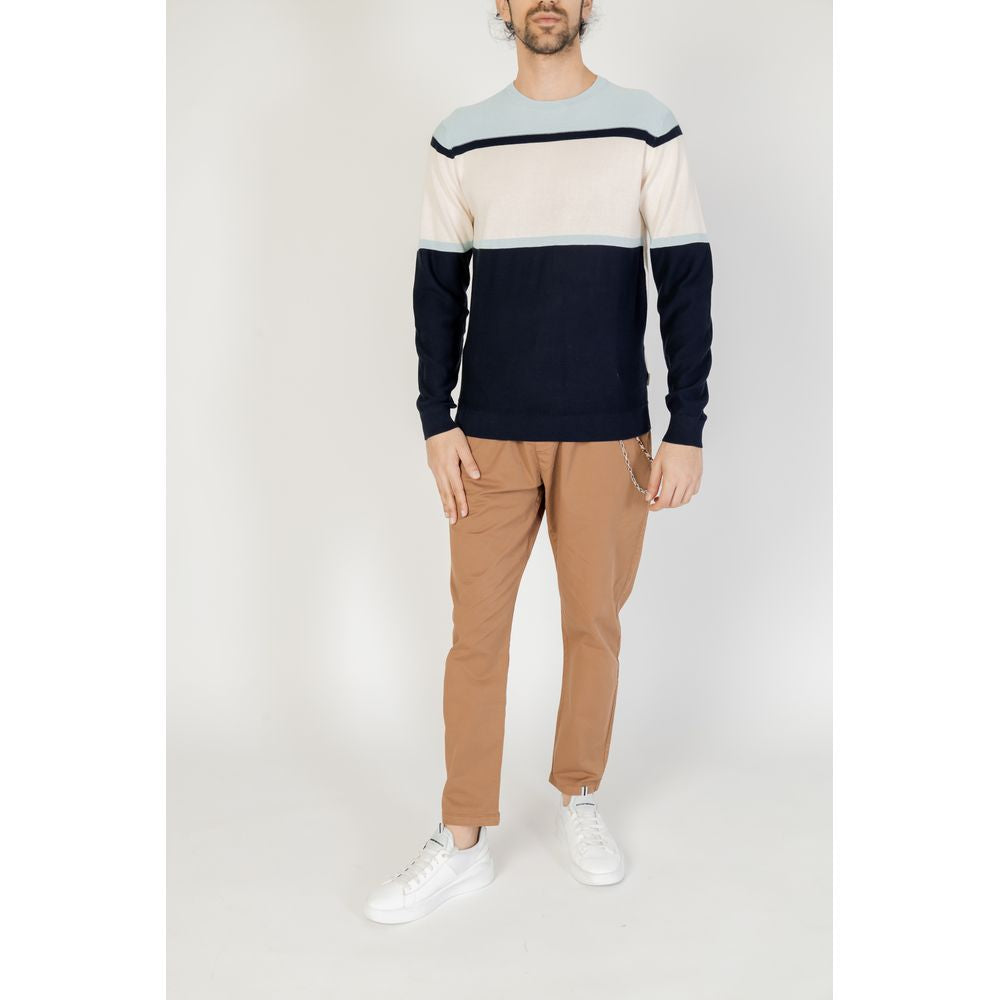 Man wearing Hamaki-Ho blue cotton t-shirt and tan pants, showcasing casual men's spring/summer fashion outfit with white sneakers.