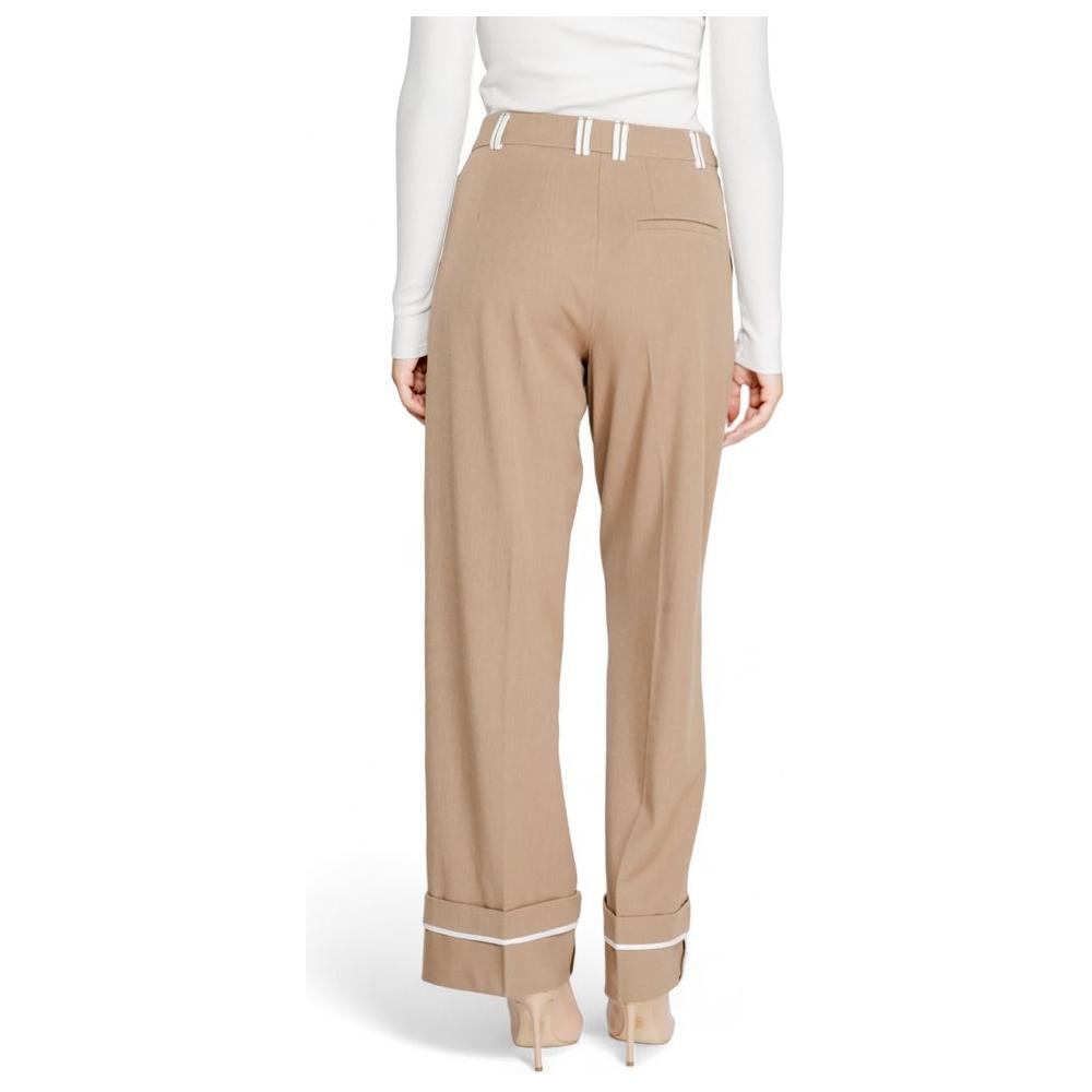Woman wearing brown recycled polyester pants from Fall Winter collection with high waist and cuffed hems, back view.