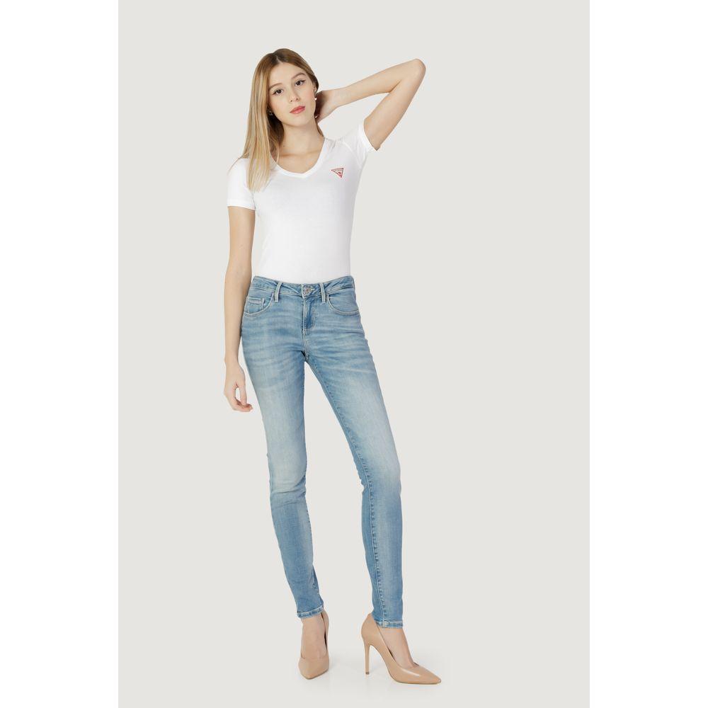 Woman wearing Guess Annette blue cotton skinny jeans, styled with a white top and heels, showcasing modern fashion and versatility.
