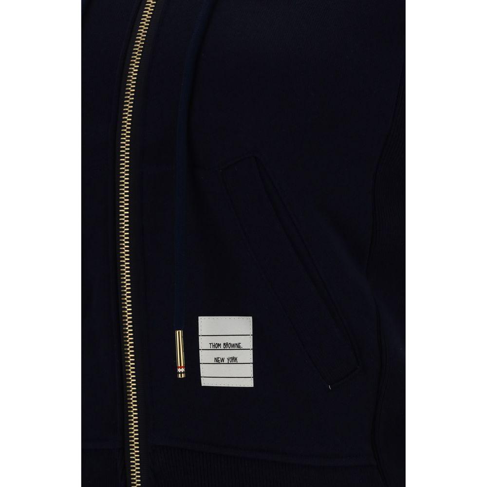 Close-up of Thom Browne cotton hoodie with zip closure, kangaroo pocket, logo patch, ribbed hem, featuring left sleeve stripe print.