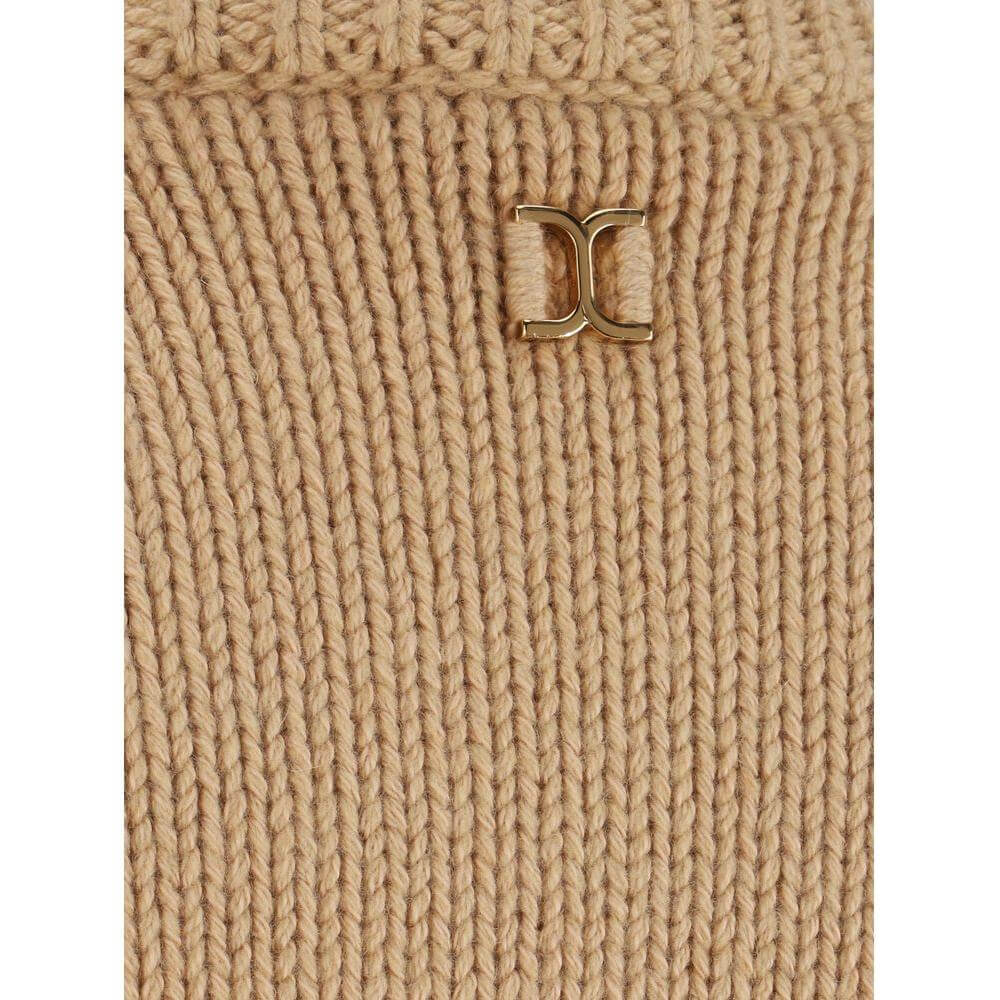 Detail of Chloé cashmere sweater showcasing ribbed texture and gold logo embellishment on a monochrome beige pattern.