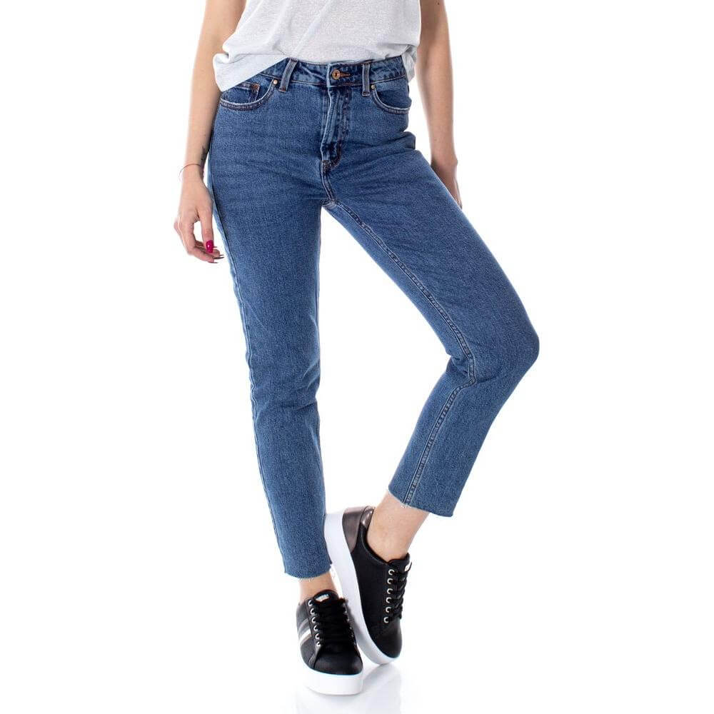 Woman wearing blue high waist cotton jeans with white shirt and black sneakers, showcasing stylish and comfortable fit.