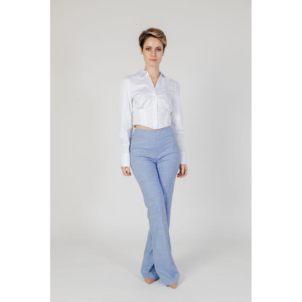 Woman wearing Guess white cotton long-sleeved shirt, part of women's collection, 97% cotton composition, styled with blue trousers.