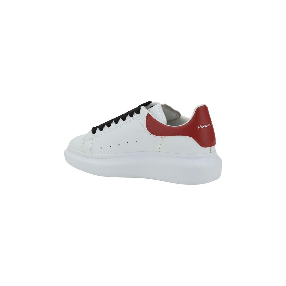 Alexander McQueen leather sneakers with contrast red heel, featuring lace-up closure, round toe, and platform sole.