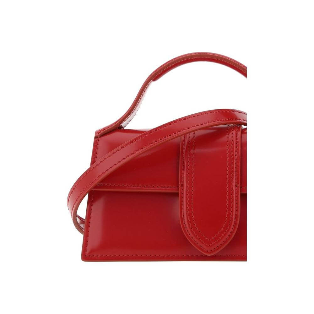 Red Jacquemus Le Bambino handbag with flat top handle and adjustable shoulder strap, featuring iconic monogram on front.