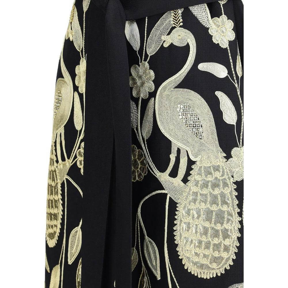 Valentino embroidered vest detail with gold nature-inspired patterns and fringed scarf on black fabric.