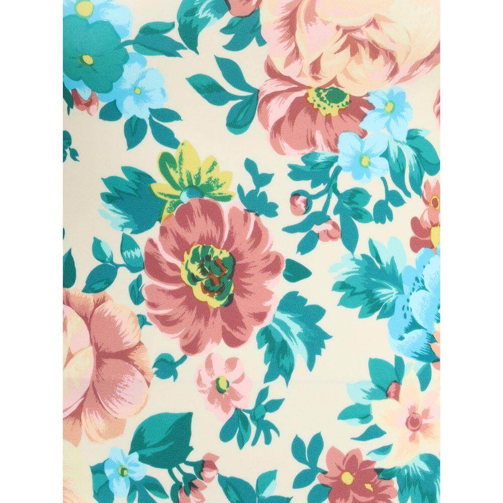 Close-up of vibrant floral print on fabric, featuring pink, yellow, and blue flowers with green leaves on a cream background.