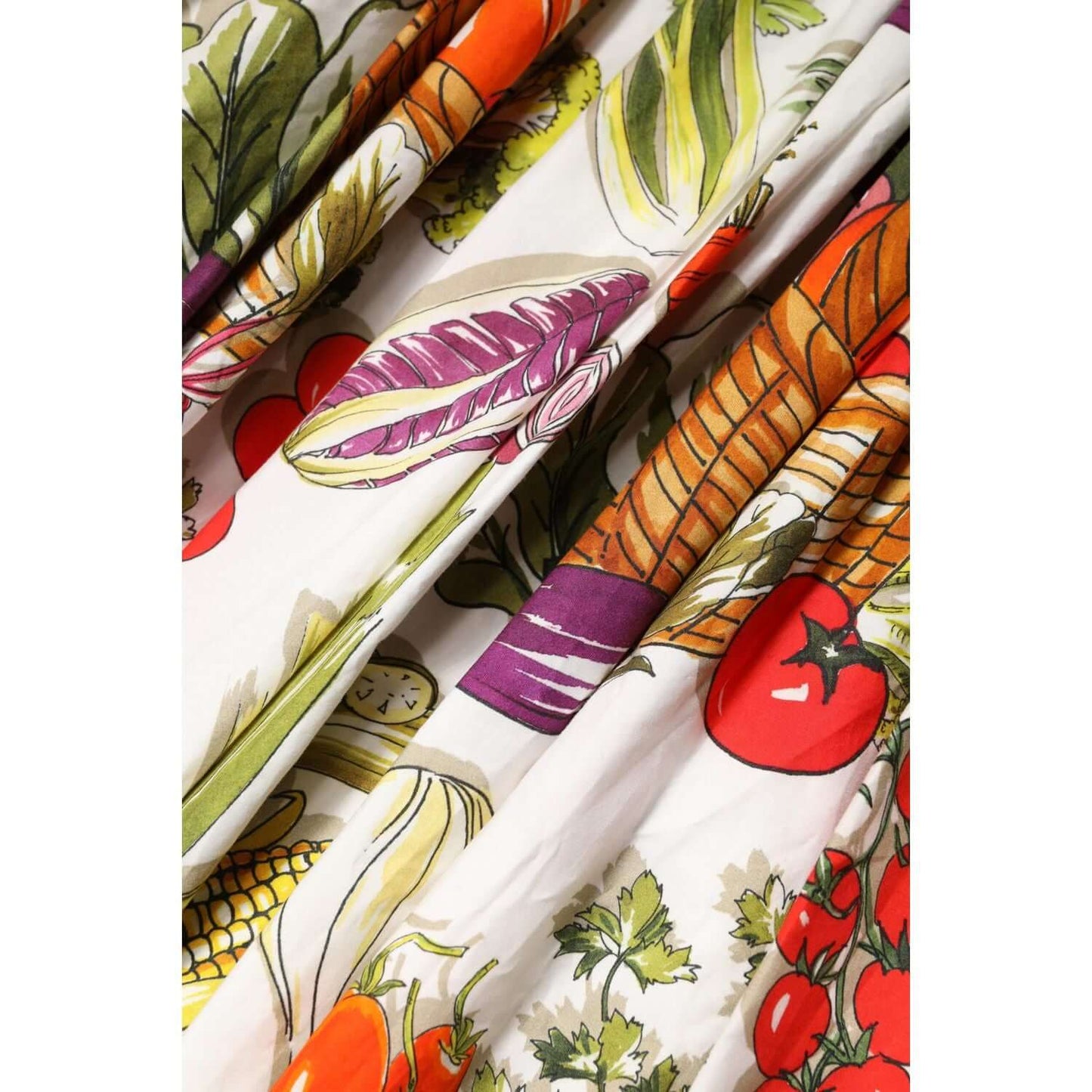 Close-up of Dolce & Gabbana white A-line dress with colorful vegetable print, featuring lettuce, carrots, and tomatoes. Made in Italy.