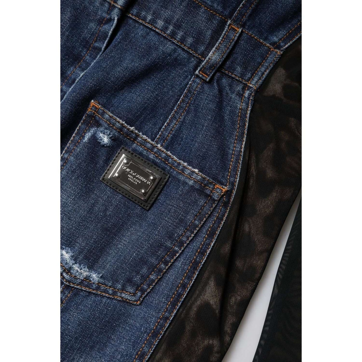 Close-up of Dolce & Gabbana denim mini dress, featuring blue and black fabric with a logo detail patch and visible stitching.
