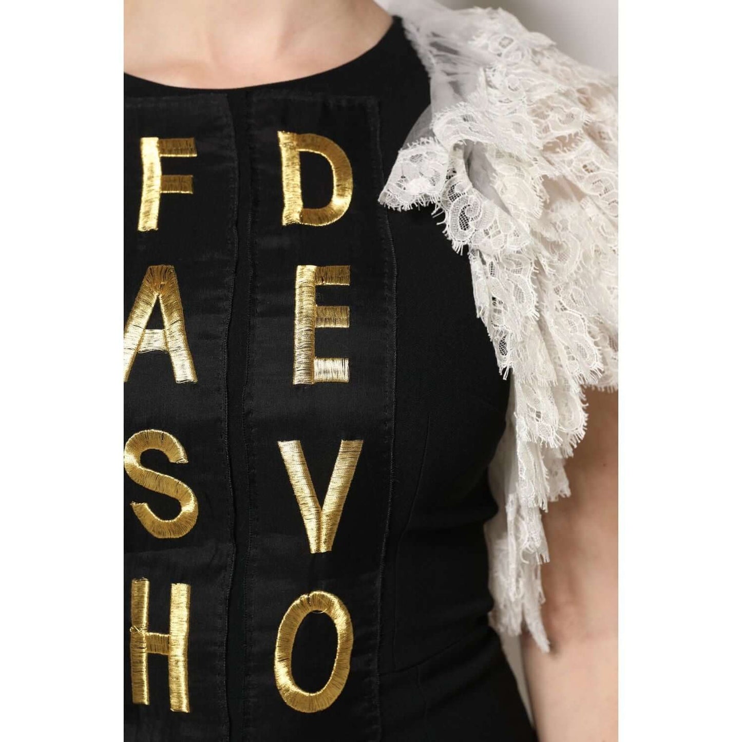 Close-up of Dolce & Gabbana black embellished mini dress with gold lettering and lace details, showcasing luxury fashion craftsmanship.