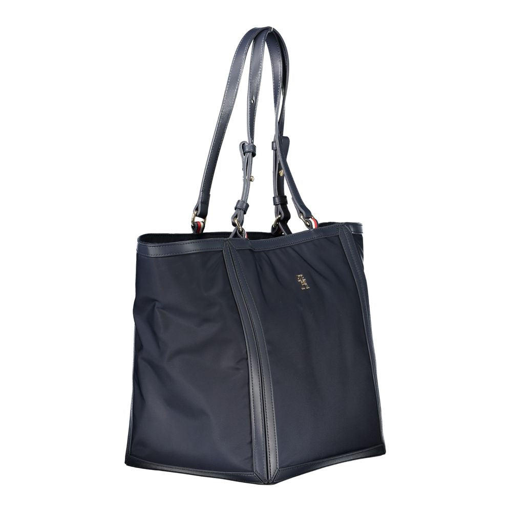 Tommy Hilfiger blue polyester handbag with adjustable shoulder handles, zip closure, and logo, featuring contrasting details and pockets.