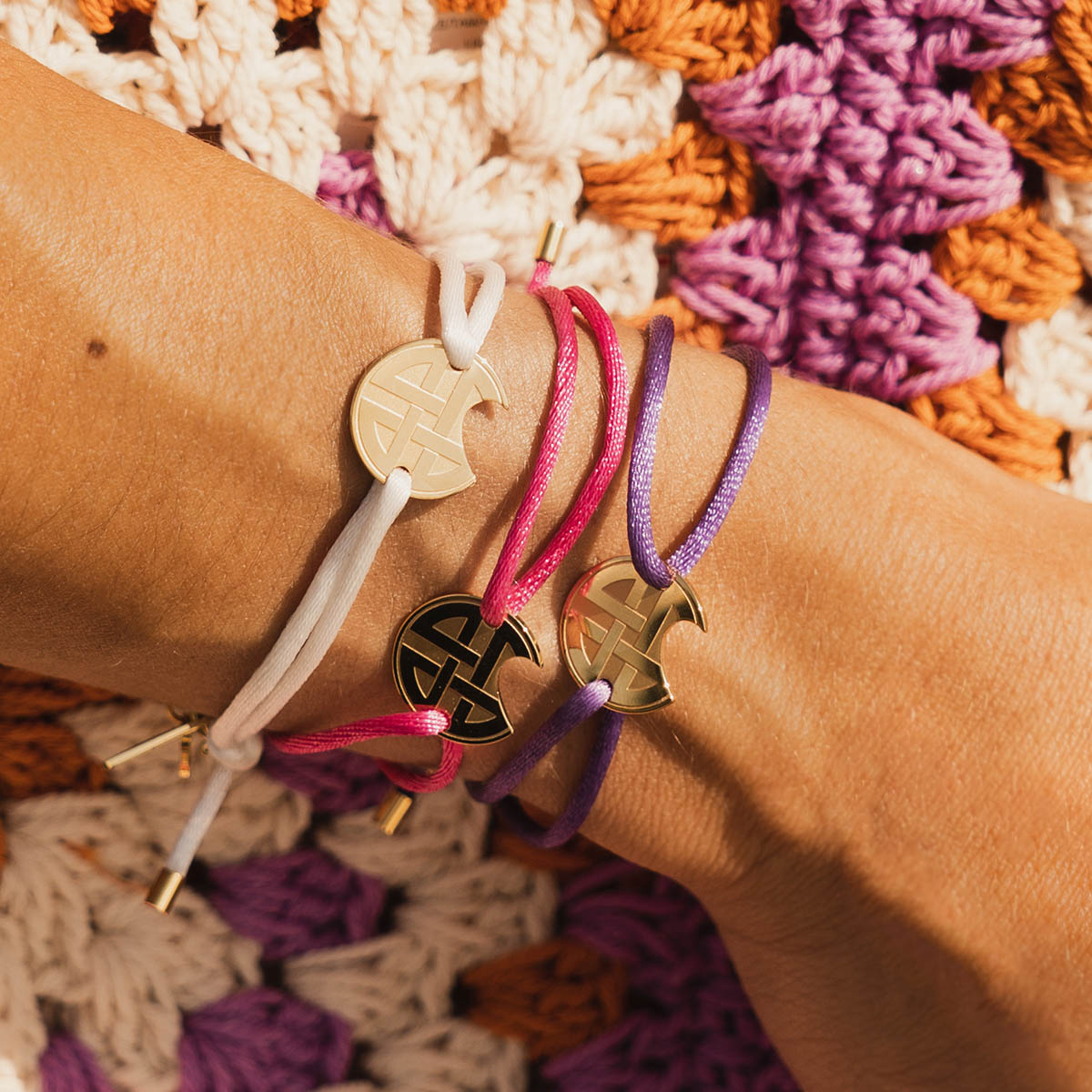 AN JEWELS JEWELRY Mod. AV.BGLBGGPK bracelet set on wrist with colorful braided strings and gold charms.