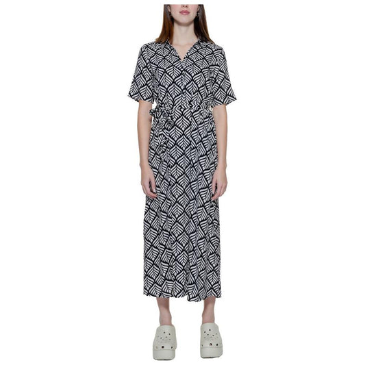 Woman wearing a black and white patterned long dress with half sleeves and a relaxed fit, paired with white clogs.