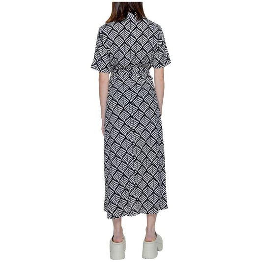 Back view of a woman wearing a long black and white patterned dress with short sleeves, paired with platform sandals.