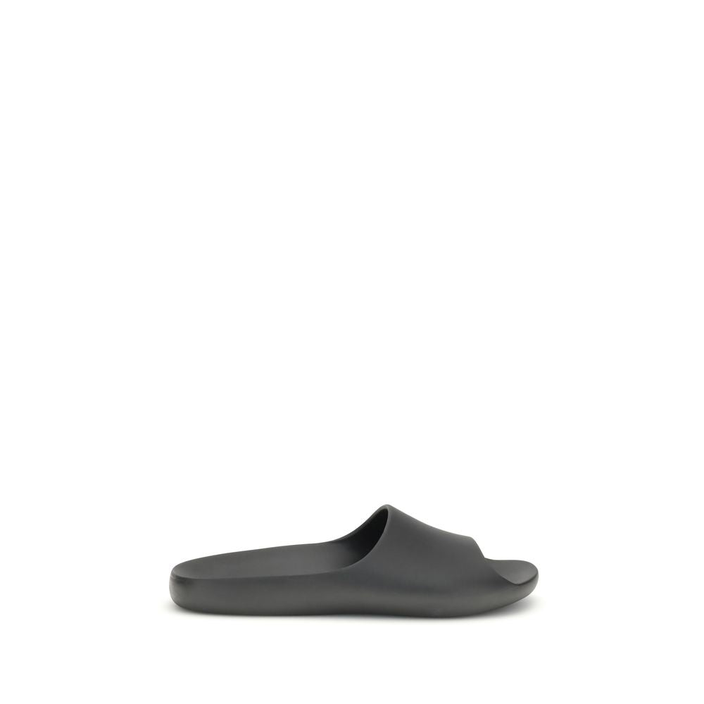 The Row Black Rubber Slippers featuring minimalistic design with contoured footbed for comfort, seamless construction, and lightweight feel.
