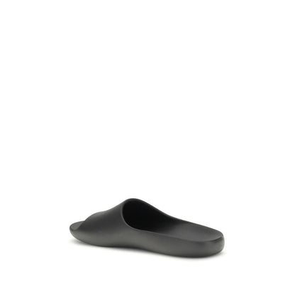The Row Black Rubber Slippers with contoured footbed, featuring minimalist design and seamless construction, ideal for understated style.