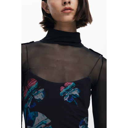 Model wearing Desigual Black Polyester Women Dress with watercolor design and thin straps, paired with a high-neck sheer long-sleeved top.
