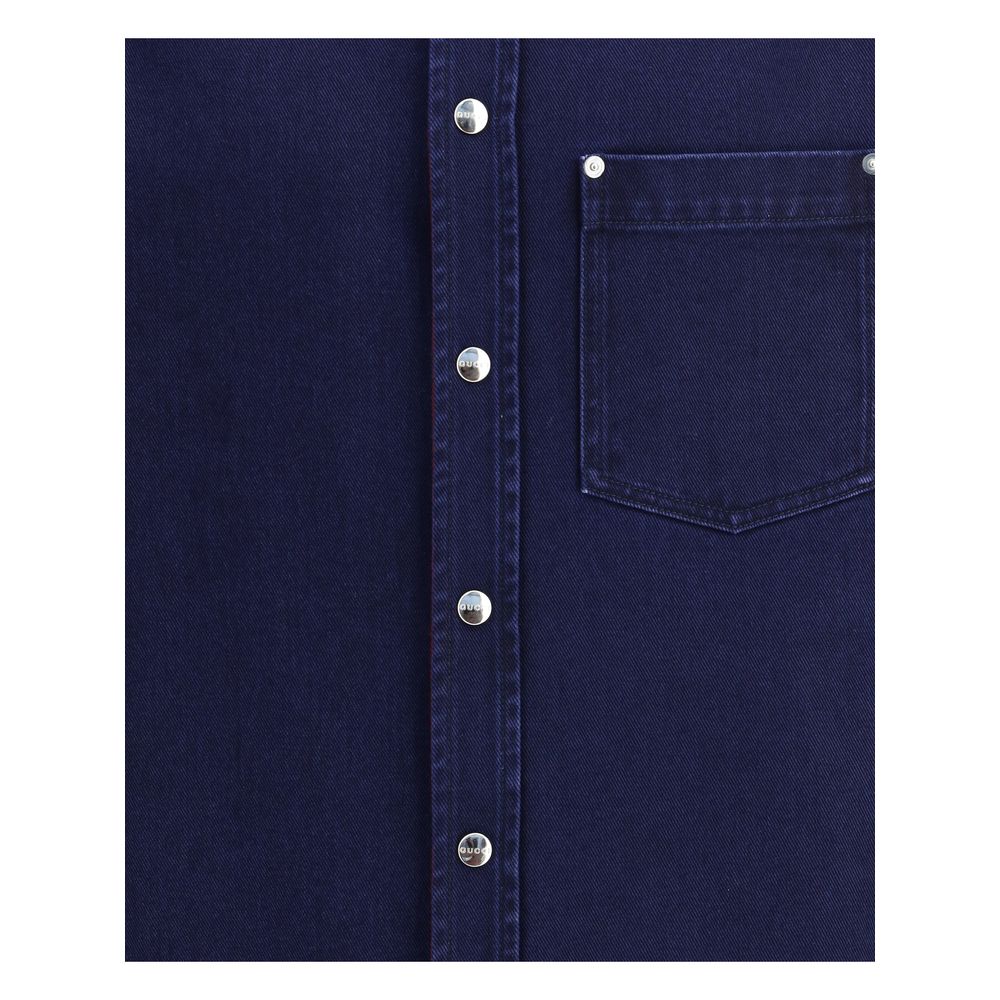 Close-up of Gucci Blue Denim Shirt with metal buttons and chest pocket, showcasing délavé denim texture for AW25 collection.