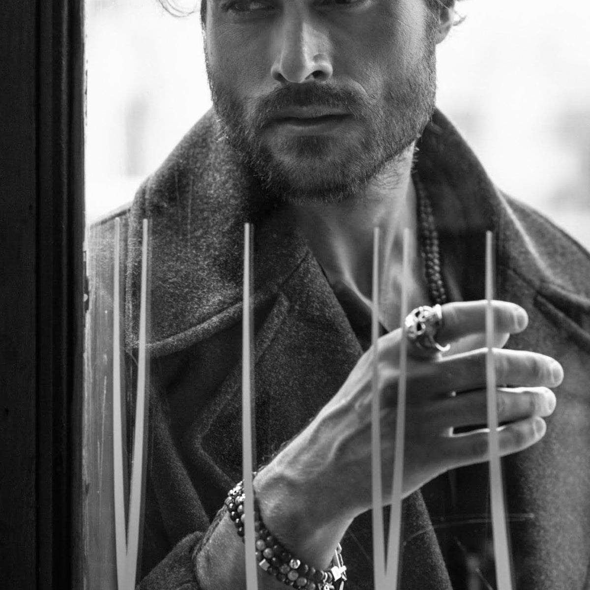 Man wearing AN JEWELS JEWELRY Mod. AA.P255SBK looking out window, showcasing stylish jewelry in black and white photo.