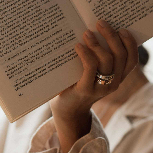 Hand holding a book while wearing AN JEWELS JEWELRY Mod. AL.RWH01SC-8 ring, showing elegant design.
