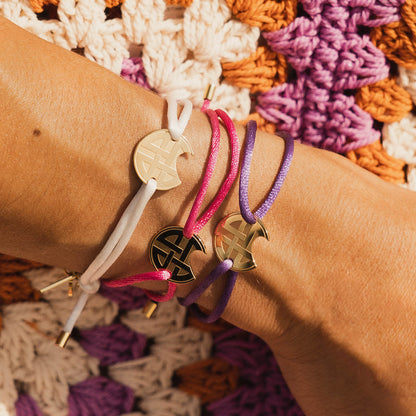 AN JEWELS JEWELRY Mod. AV.BGLBGGPK bracelet set on wrist with colorful braided strings and gold charms.