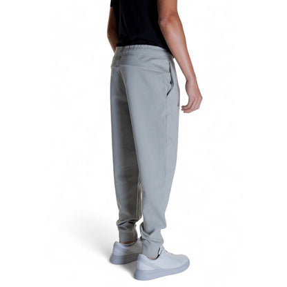 Man wearing Calvin Klein Gray Cotton Joggers (Workout Pants) with white sneakers, showcasing back design for style and comfort.