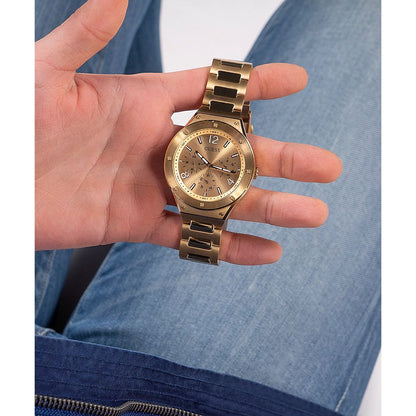 Luxury gold watch held in a hand over blue jeans, featuring sleek design and precise timekeeping.
