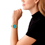 Woman wearing MICHAEL KORS Mod. LENNOX gold wristwatch with blue dial, 39mm case, wrist view, elegant design for ladies.