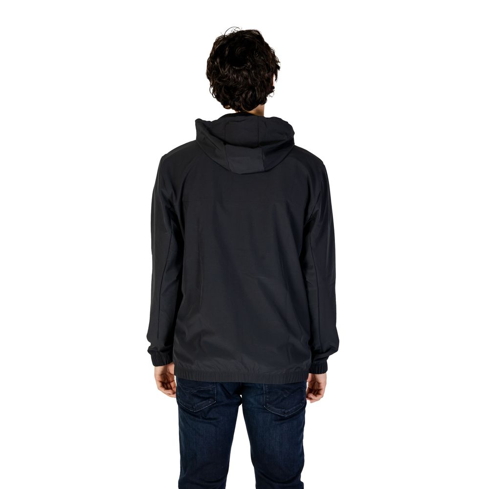 Back view of man wearing New Balance Black Recycled Polyester Shell Jacket with hood, showcasing lightweight and wind protection features.