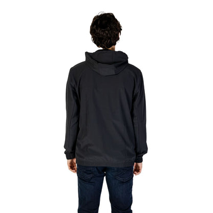 Back view of man wearing New Balance Black Recycled Polyester Shell Jacket with hood, showcasing lightweight and wind protection features.