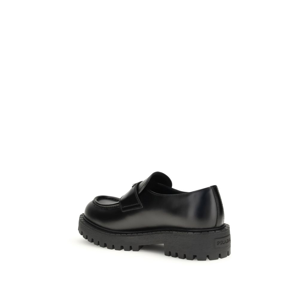 Prada Black Calf Leather Bos Taurus Slip-On Loafers with enameled triangle detail and rubber sole, showcasing AW25 fashion style.