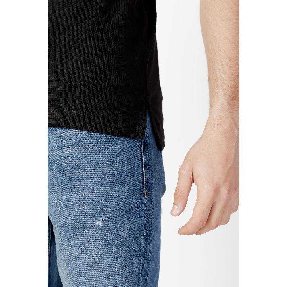 Close-up of a man wearing a Tommy Hilfiger Jeans Black Cotton Polo Shirt with blue jeans, highlighting the slim fit and short sleeves.