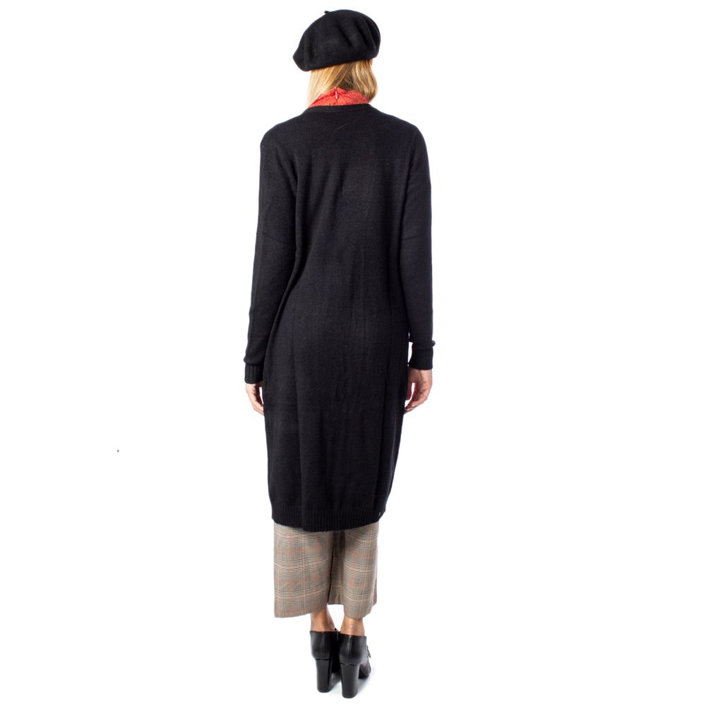 Back view of a woman wearing a Vila Clothes Black Viscose Cardigan with a beret and check pants, standing against a white background.